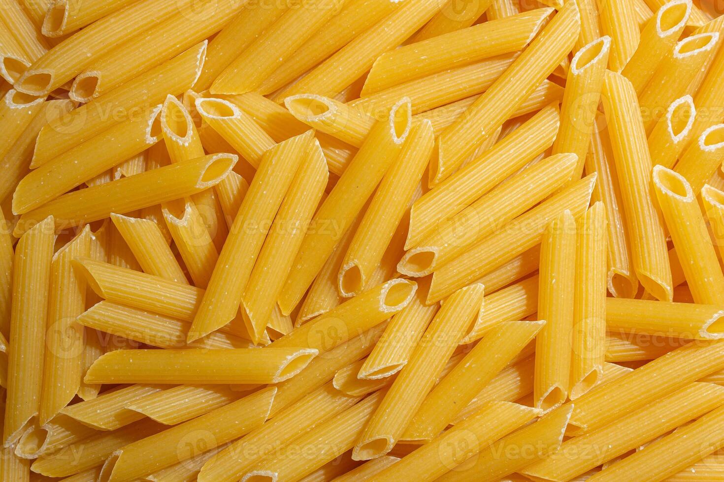 Uncooked Penne Rigate Pasta. A Culinary Canvas of Penne Macaroni, Creating a Lively and Textured Background for Gourmet Cooking. Dry Pasta. Raw Macaroni - Top View, Flat Lay photo