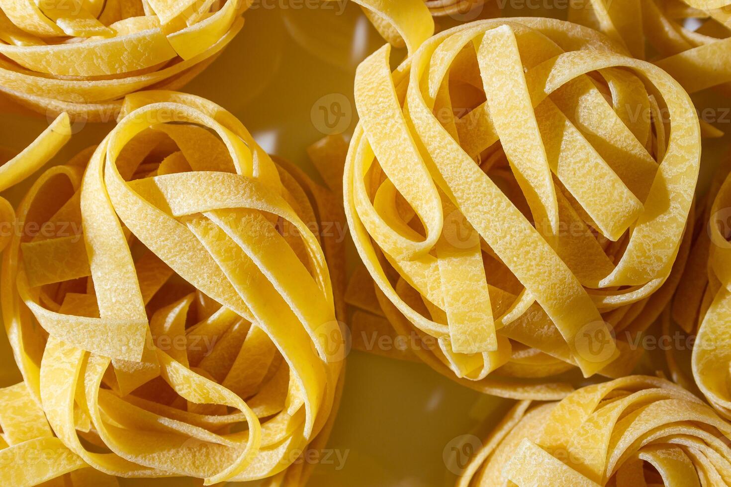 Uncooked Egg-Based Fettuccine Pasta. A Culinary Canvas of Ribbon-Shaped Macaroni, Creating a Lively and Textured Background for Gourmet Cooking. Dry Pasta. Raw Macaroni - Top View, Flat Lay photo
