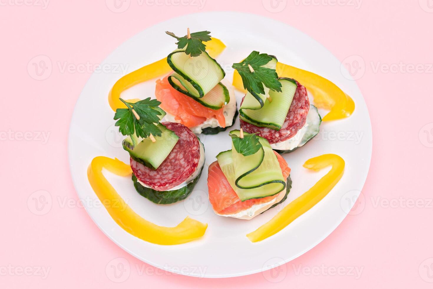 Canapes without Bread with Fresh Salmon, Salami, Cucumber, Greens and Cream Cheese on White Plate - Isolated on White. Easy Breakfast. Diet Food. Quick and Healthy Sandwiches and Snacks photo