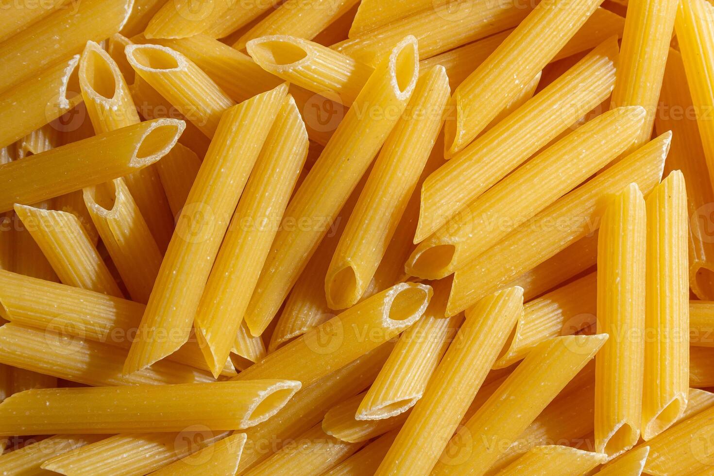 Uncooked Penne Rigate Pasta. A Culinary Canvas of Penne Macaroni, Creating a Lively and Textured Background for Gourmet Cooking. Dry Pasta. Raw Macaroni - Top View, Flat Lay photo