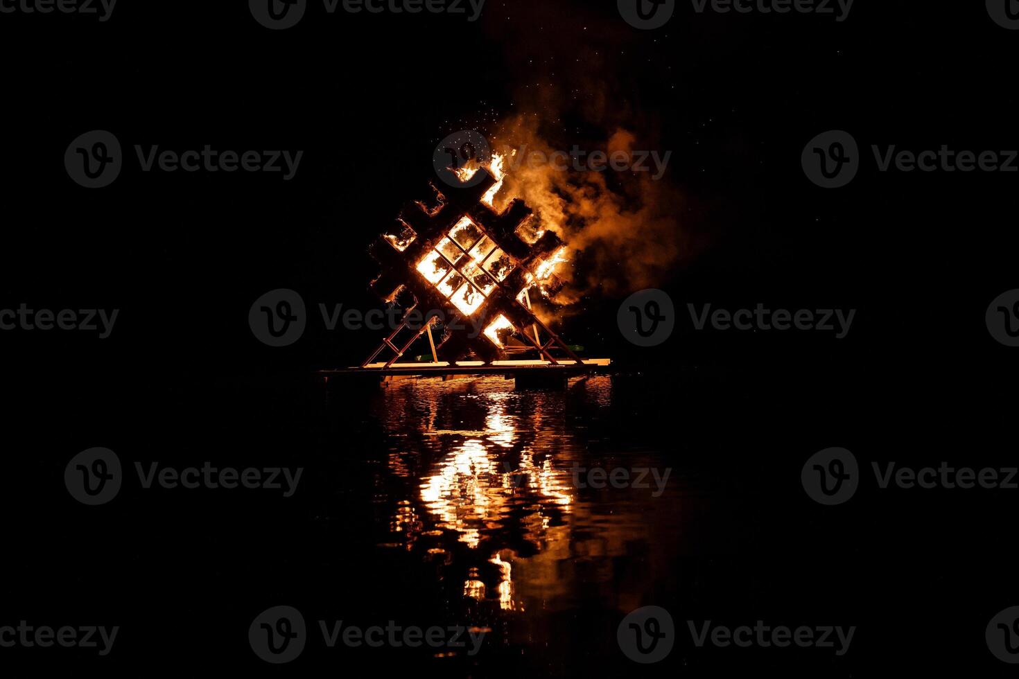 Geometric Wooden Structure Ablaze on Water at Night photo