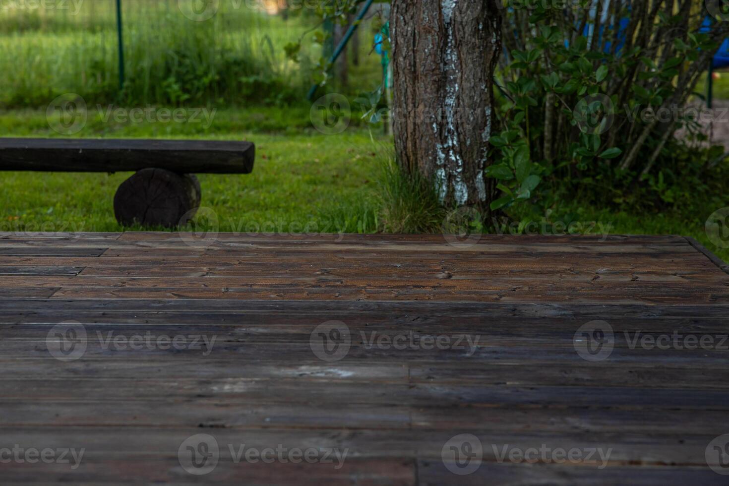 Wooden deck with central sandpit in a backyard setting, surrounded by trees and natural surroundings photo