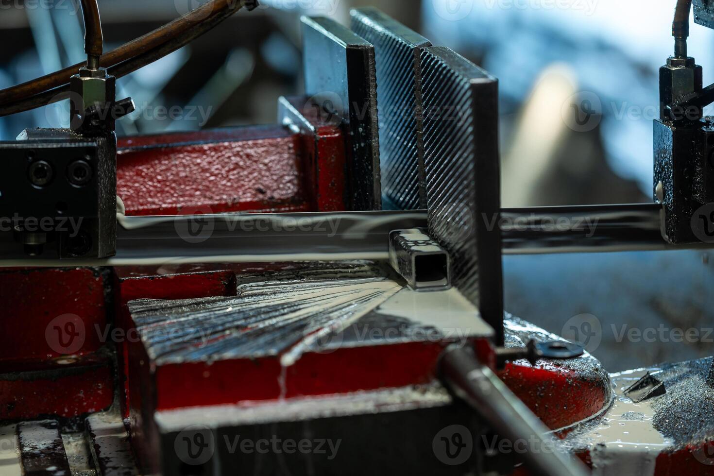 Detailed view of a red metalworking machine in a factory, cutting a metal piece with coolant fluid. Focus on precision and technical aspects of the process. photo
