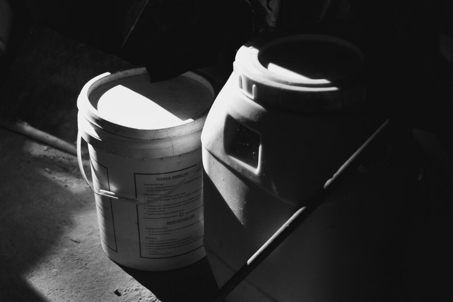 2 black and white trash cans illuminated by light from the side photo