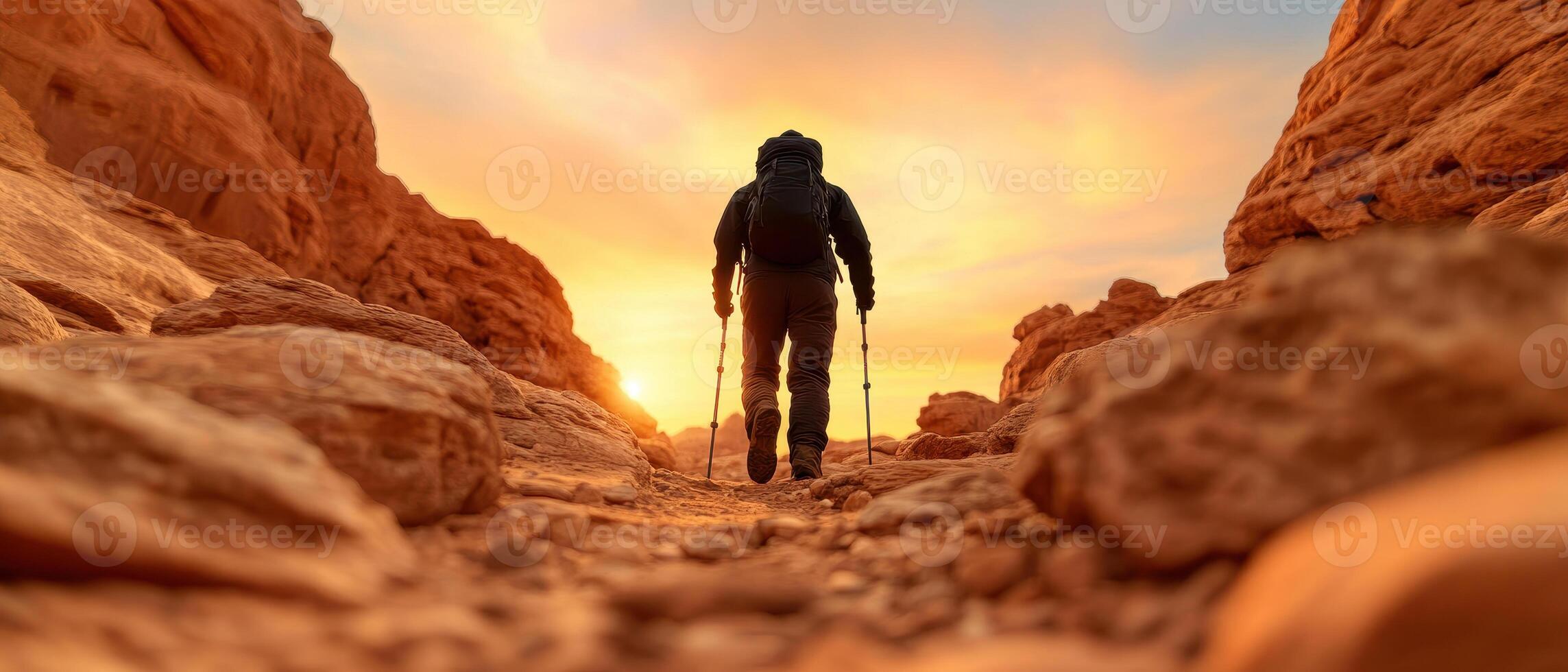 hiker traverses rocky canyon at sunset, surrounded by stunning rock formations. warm glow of sun creates serene atmosphere, perfect for adventure photo