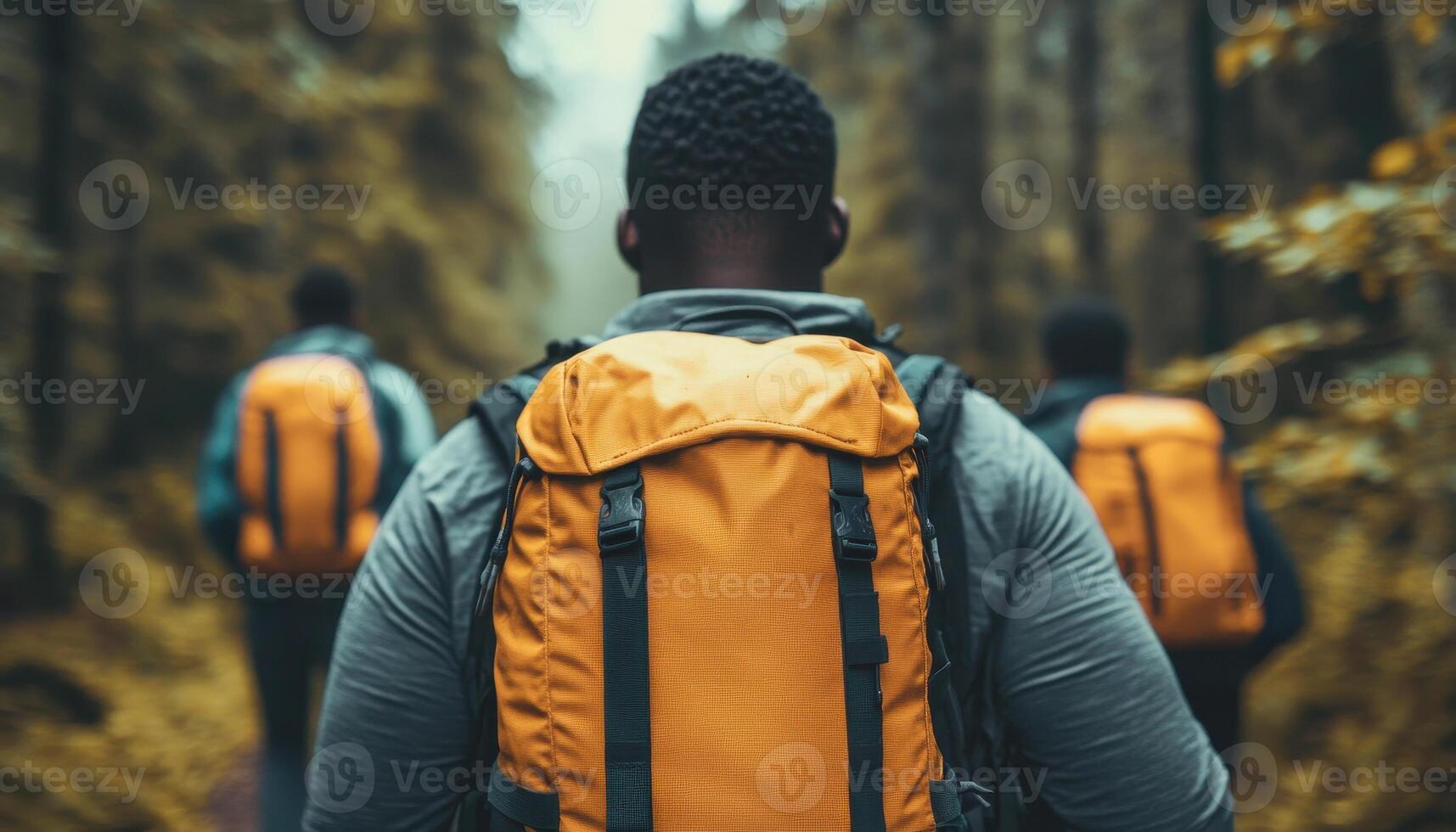Group of Black travelers hiking through dense forest, showcasing adventure and camaraderie. vibrant orange backpacks stand out against lush greenery photo