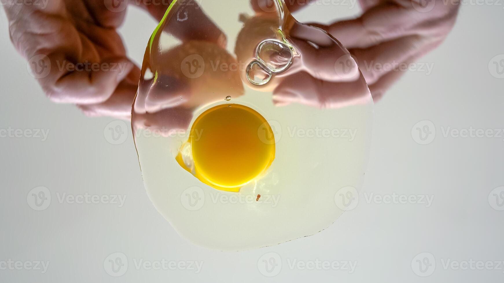 Cracking chicken egg on transparent surface. photo