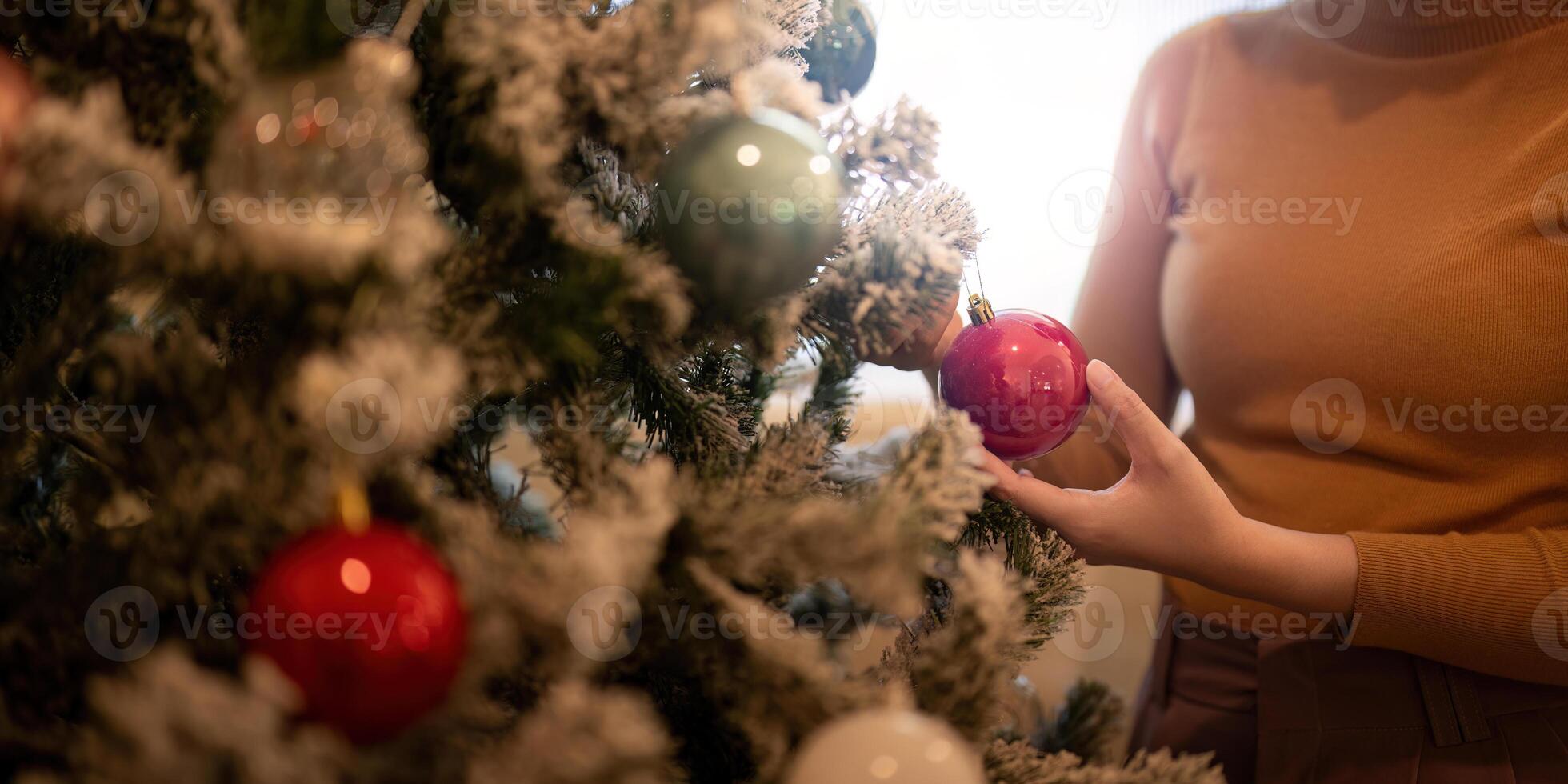 Festive Decorator Placing Ornaments on Christmas Tree for Holiday Spirit photo
