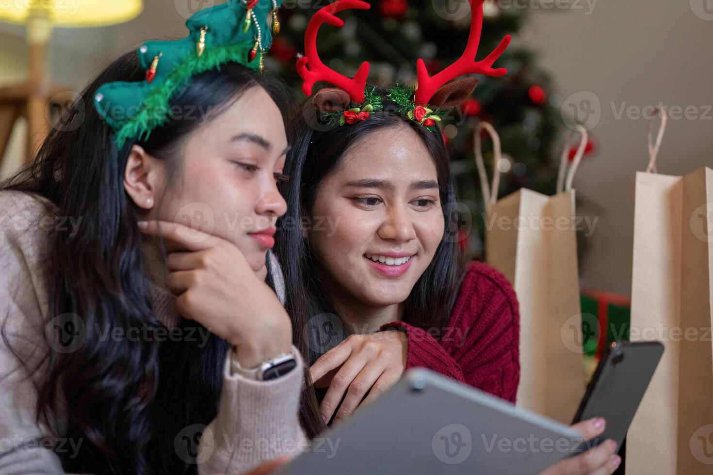 Focused Lesbian Couple Engaging with Festive Technology in Christmas Setting photo