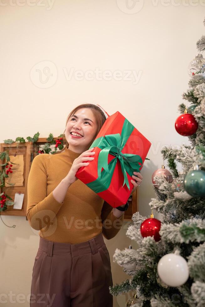 Joyful Woman Holding Festive Gift Next to Christmas Tree photo