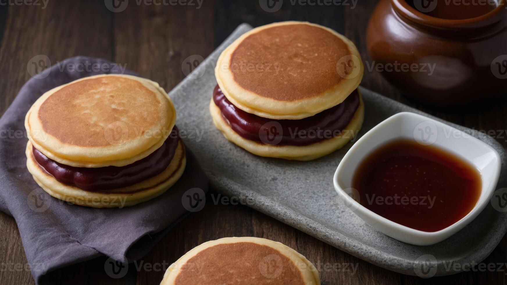 A plate of fluffy pancakes filled with sweet red bean paste and served with a dipping sauce. photo