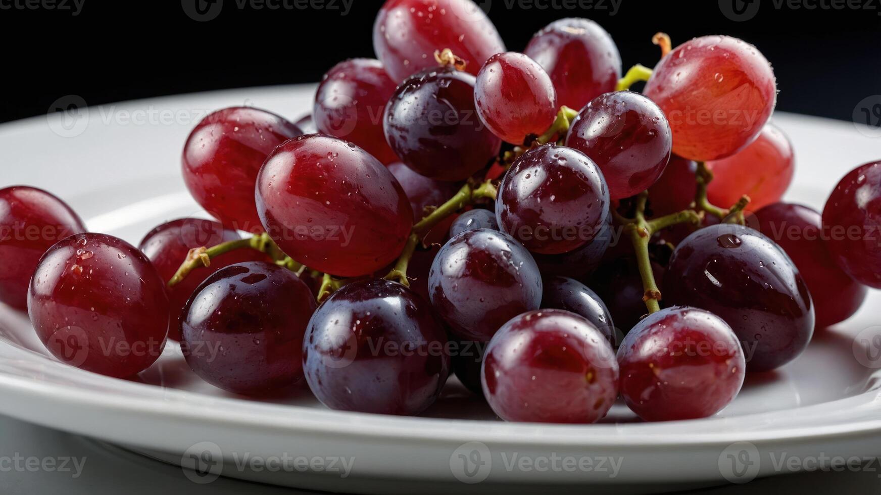 A plate of fresh red and purple grapes, glistening with moisture. photo