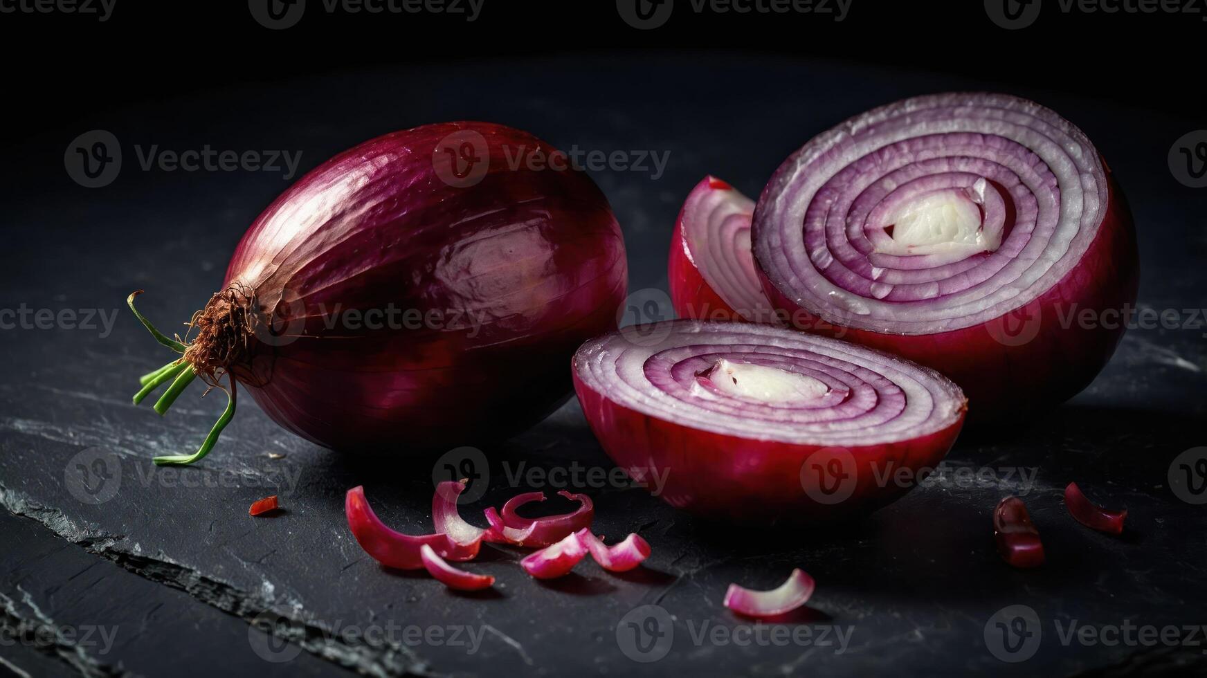 A red onion, whole and sliced, displayed on a dark surface for culinary purposes. photo