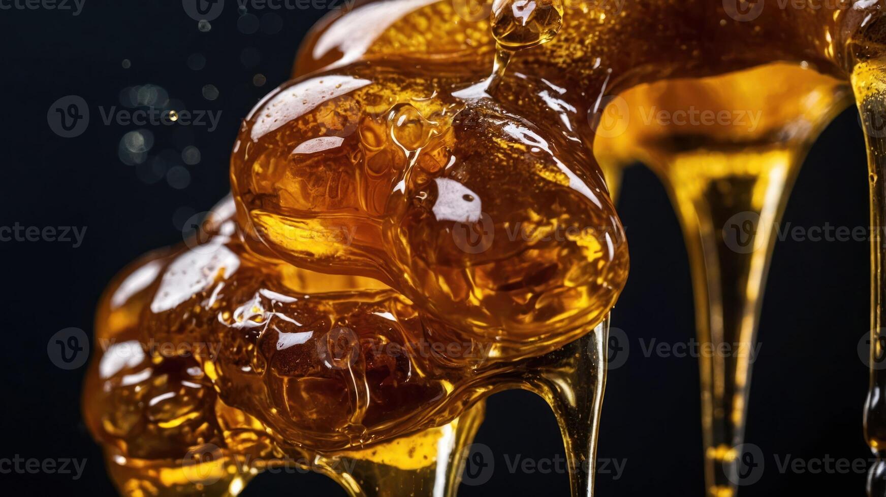 Close-up of golden honey dripping with bubbles against a dark background. photo