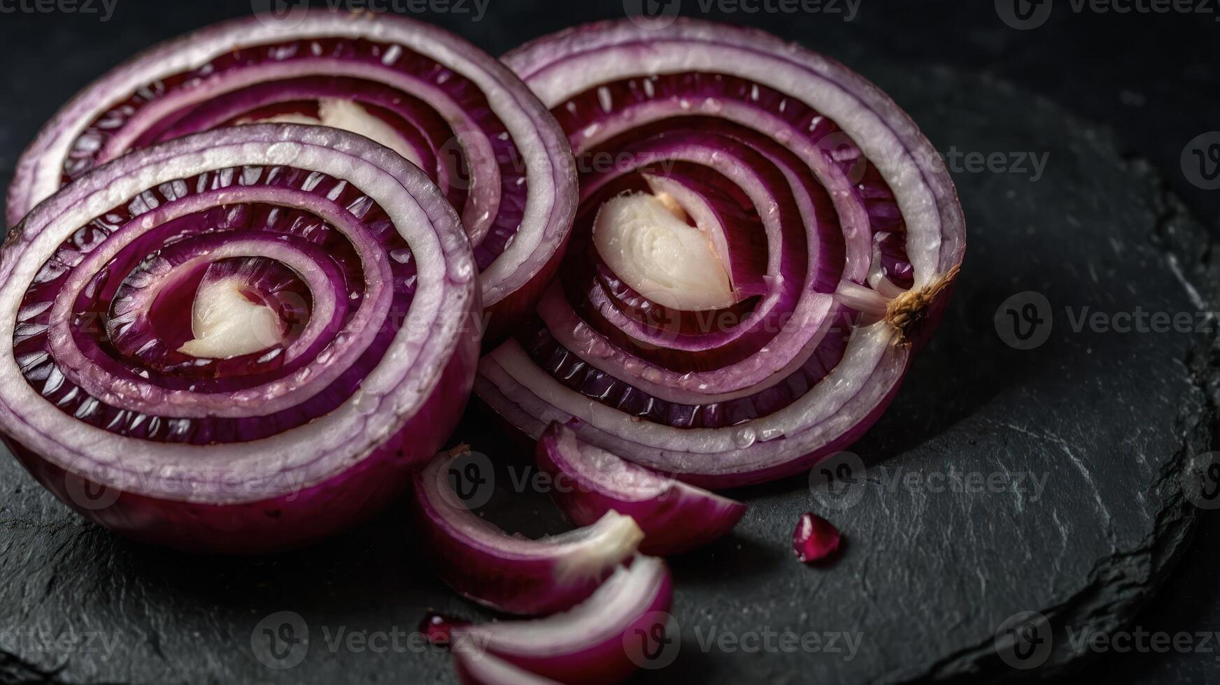 Sliced red onions arranged on a dark slate surface, showcasing their vibrant colors and texture. photo