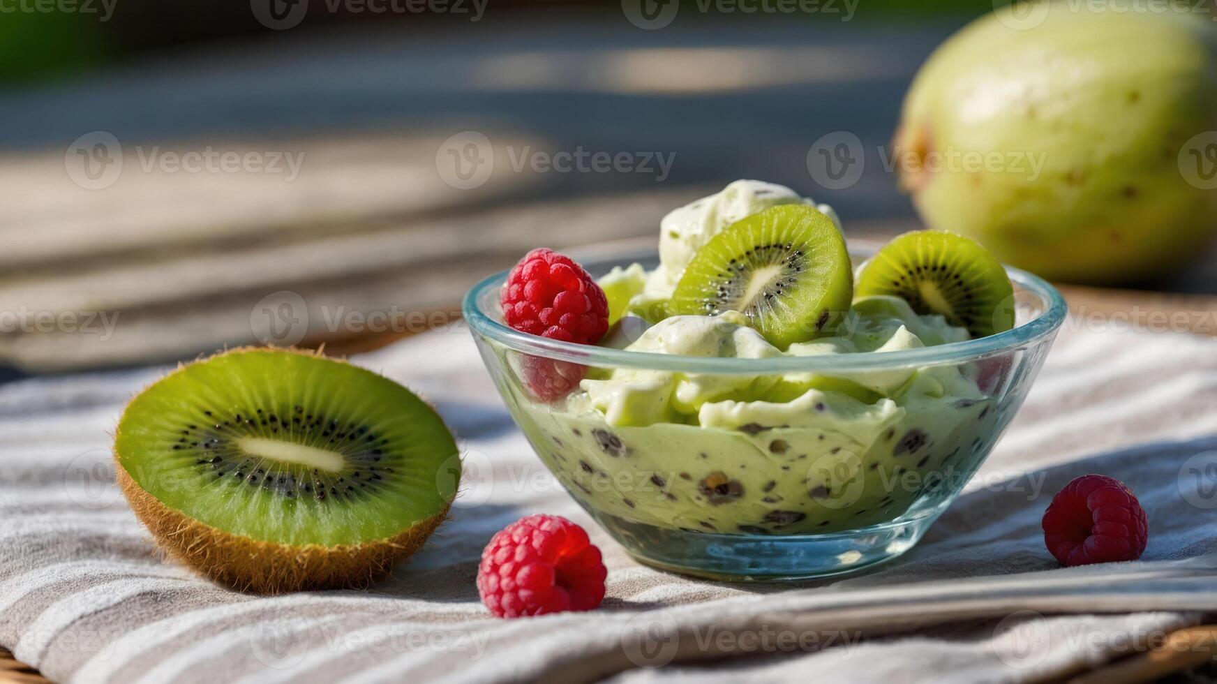 A bowl of green dessert topped with kiwi slices and raspberries on a textured cloth. photo