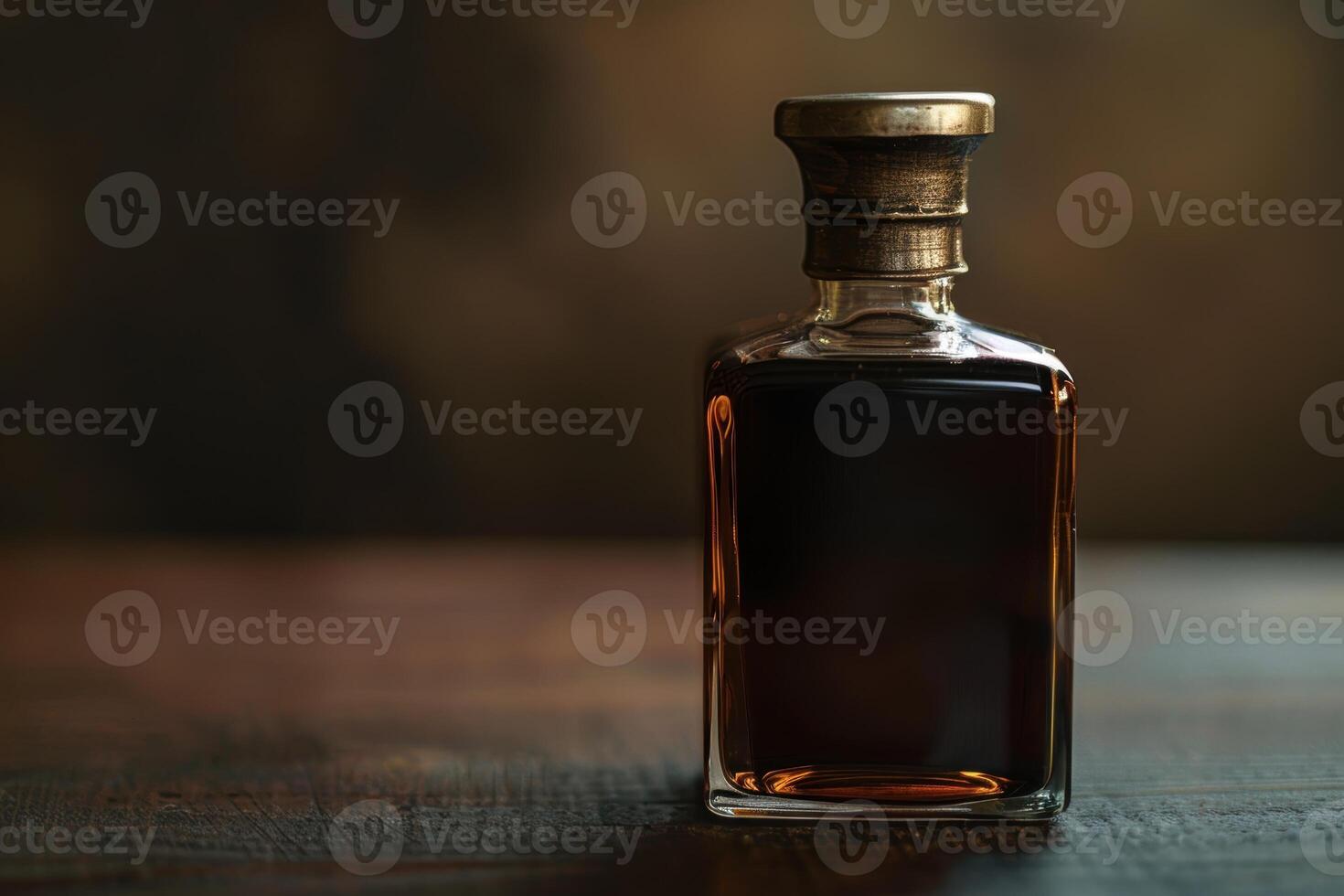 Elegant glass bottle of amber colored liquor on wooden table photo