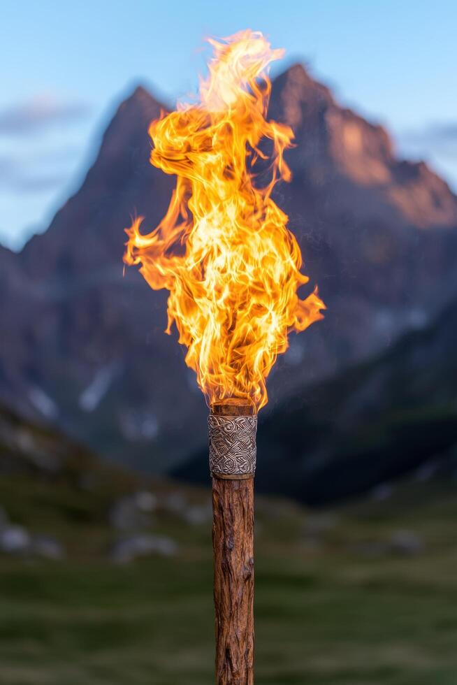 Burning wooden torch against mountain backdrop photo