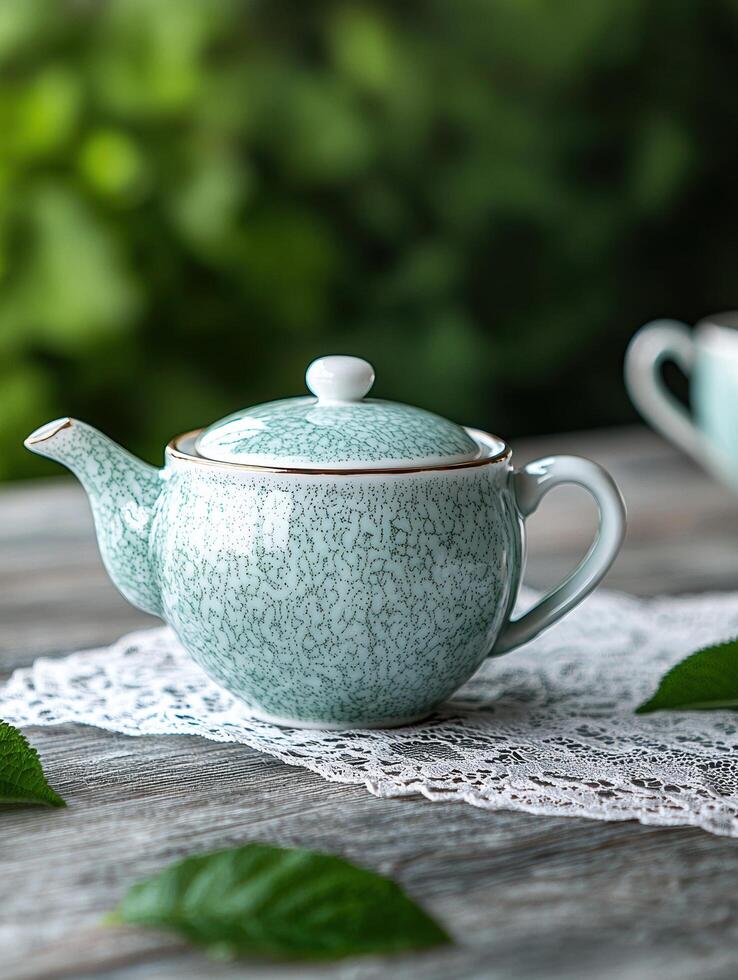 Vintage ceramic teapot on lace doily with green leaves photo