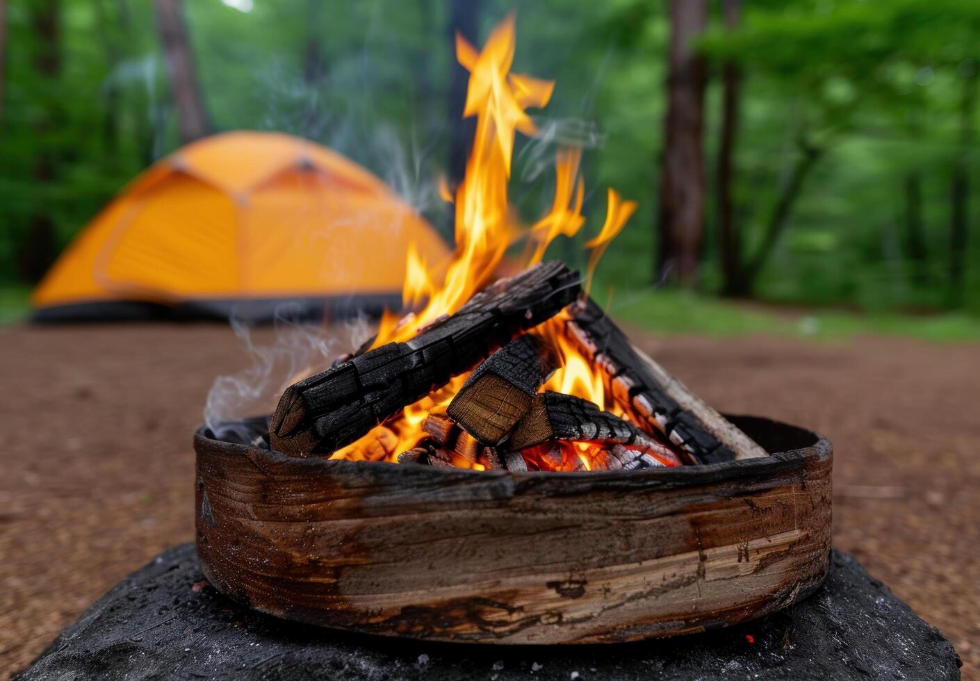 Campfire in the forest with a tent in the background photo