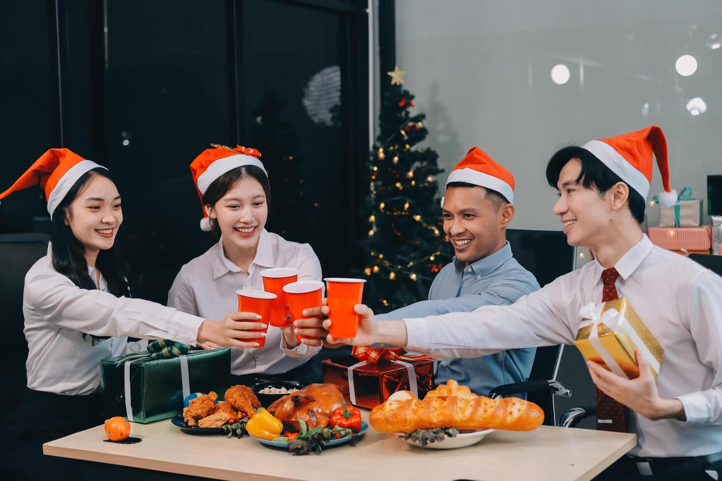 full length view of a group of business team wearing red Santa hat and exchange gift box together in the office for Christmas. photo