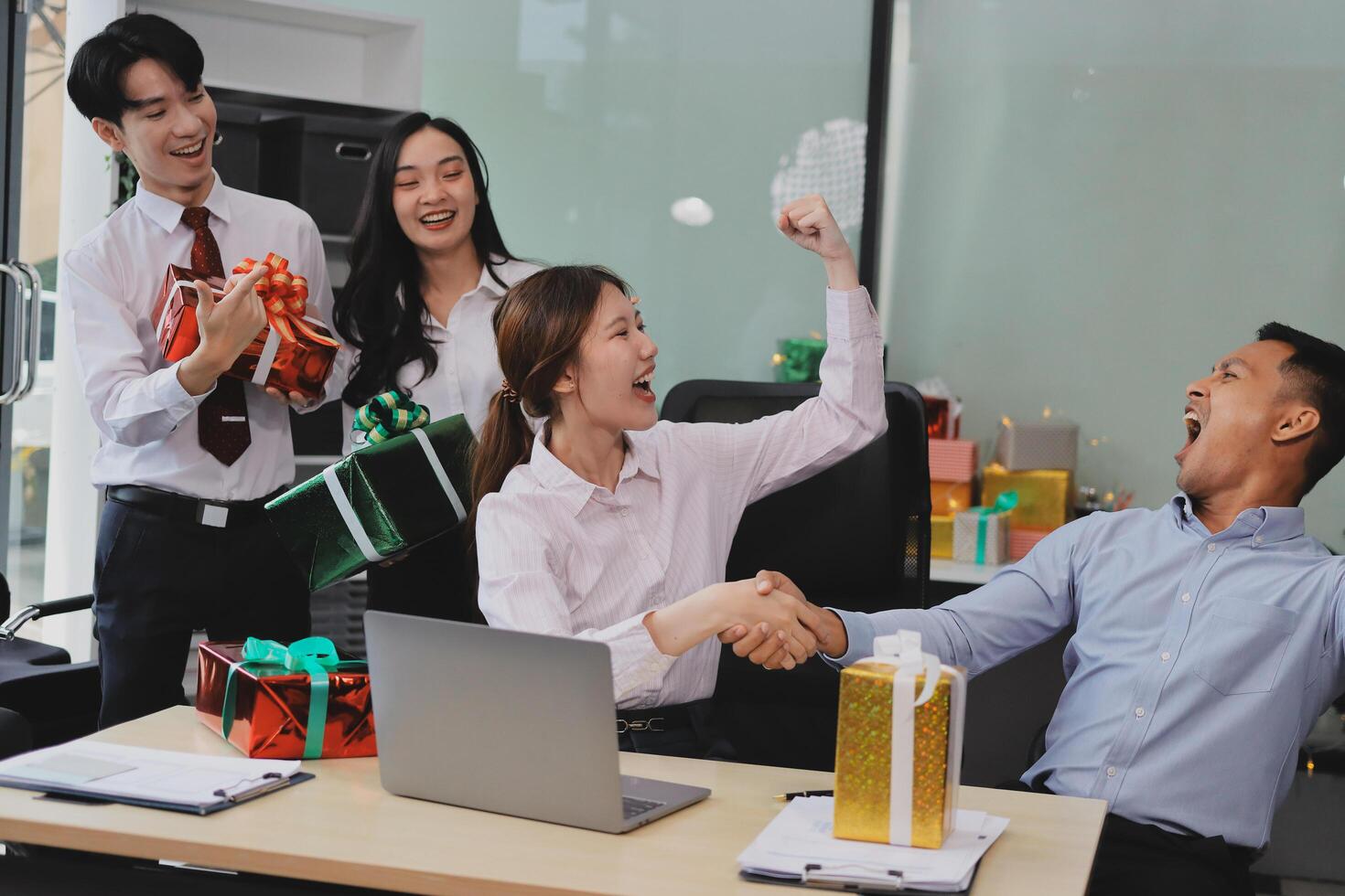 full length view of a group of business team wearing red Santa hat and exchange gift box together in the office for Christmas. photo