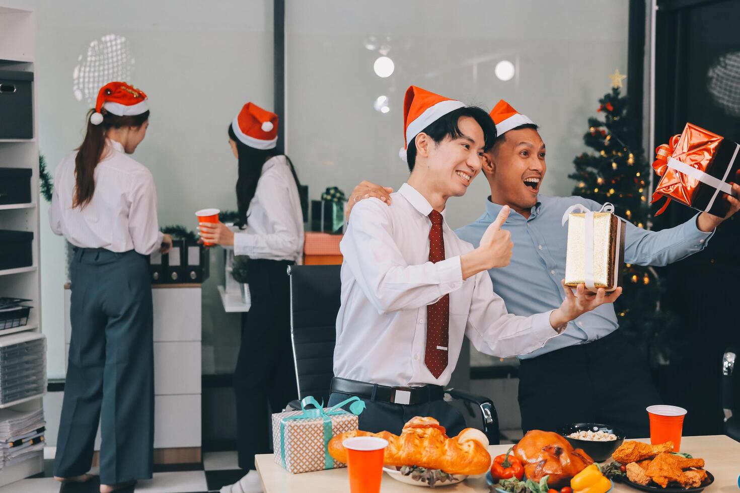 full length view of a group of business team wearing red Santa hat and exchange gift box together in the office for Christmas. photo