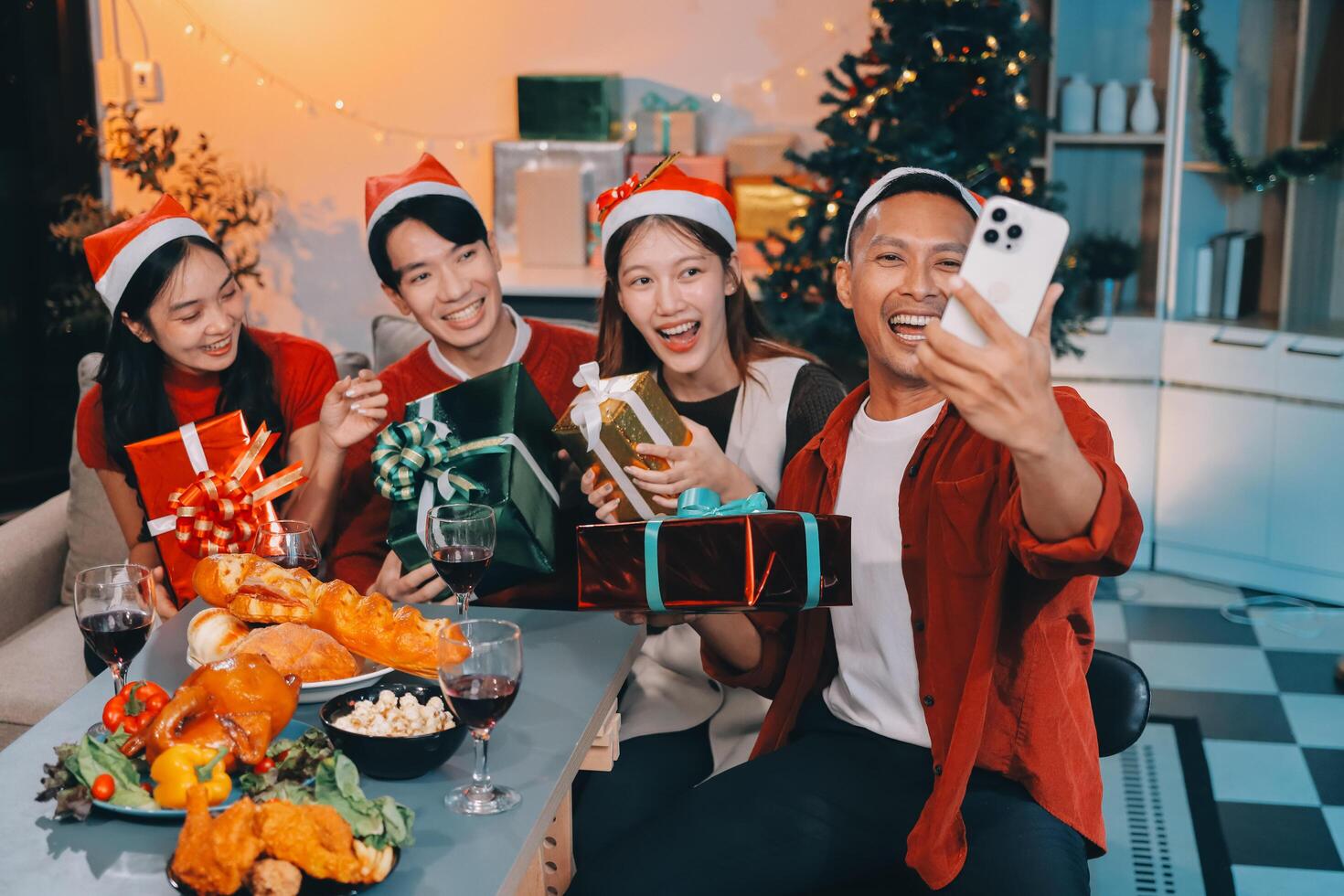 grupo de joven asiático hombre y mujer como amigos teniendo divertido a un nuevo años celebracion, participación regalo cajas en pie por Navidad árbol decoración, medianoche cuenta regresiva fiesta a hogar con fiesta estación. foto