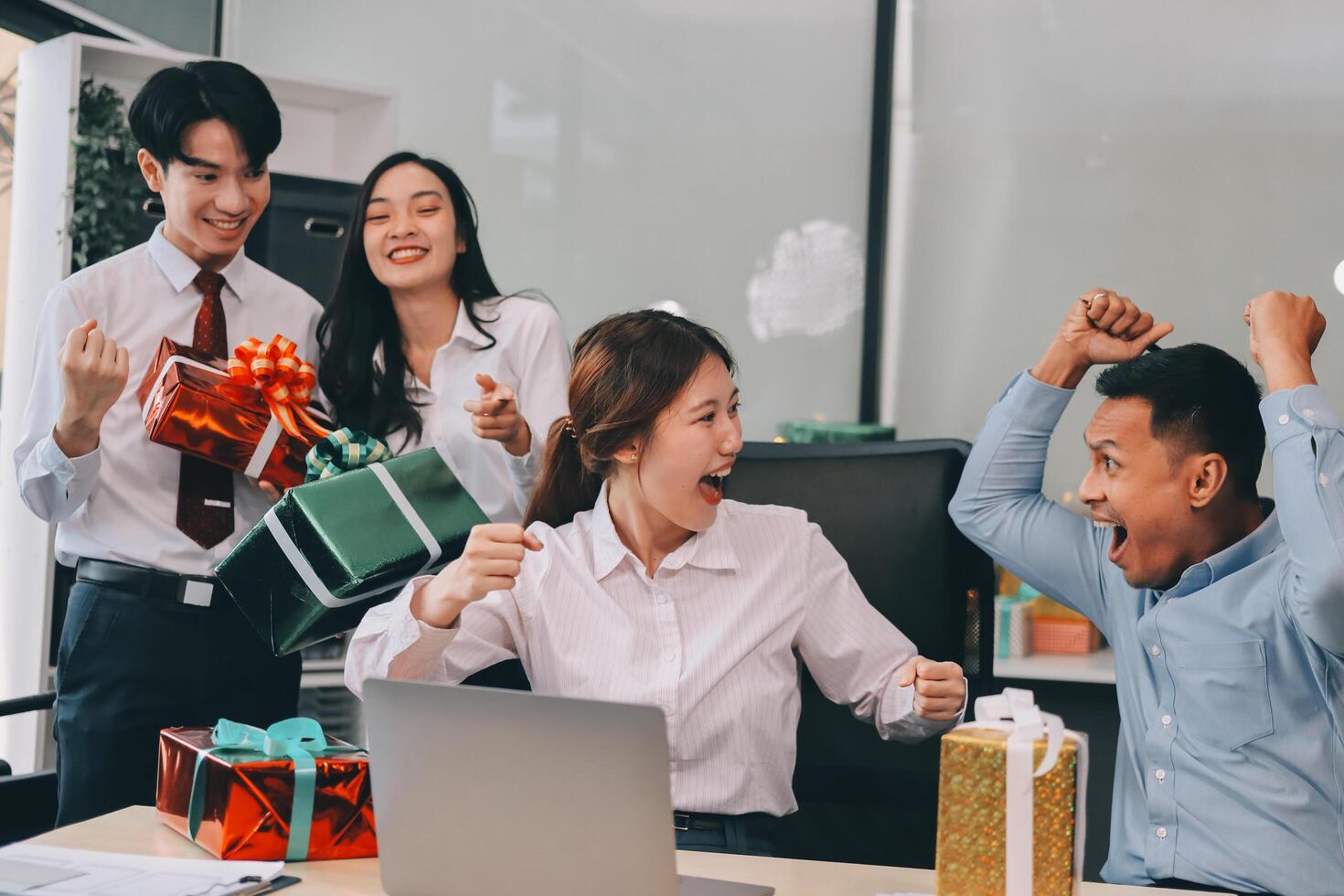 full length view of a group of business team wearing red Santa hat and exchange gift box together in the office for Christmas. photo