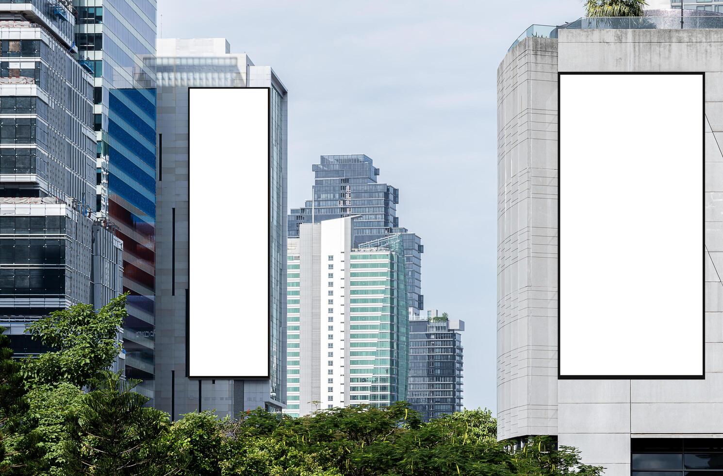 Two white mock up vertical large LED display billboard on tower building with blue sky background .clipping path for mockup photo