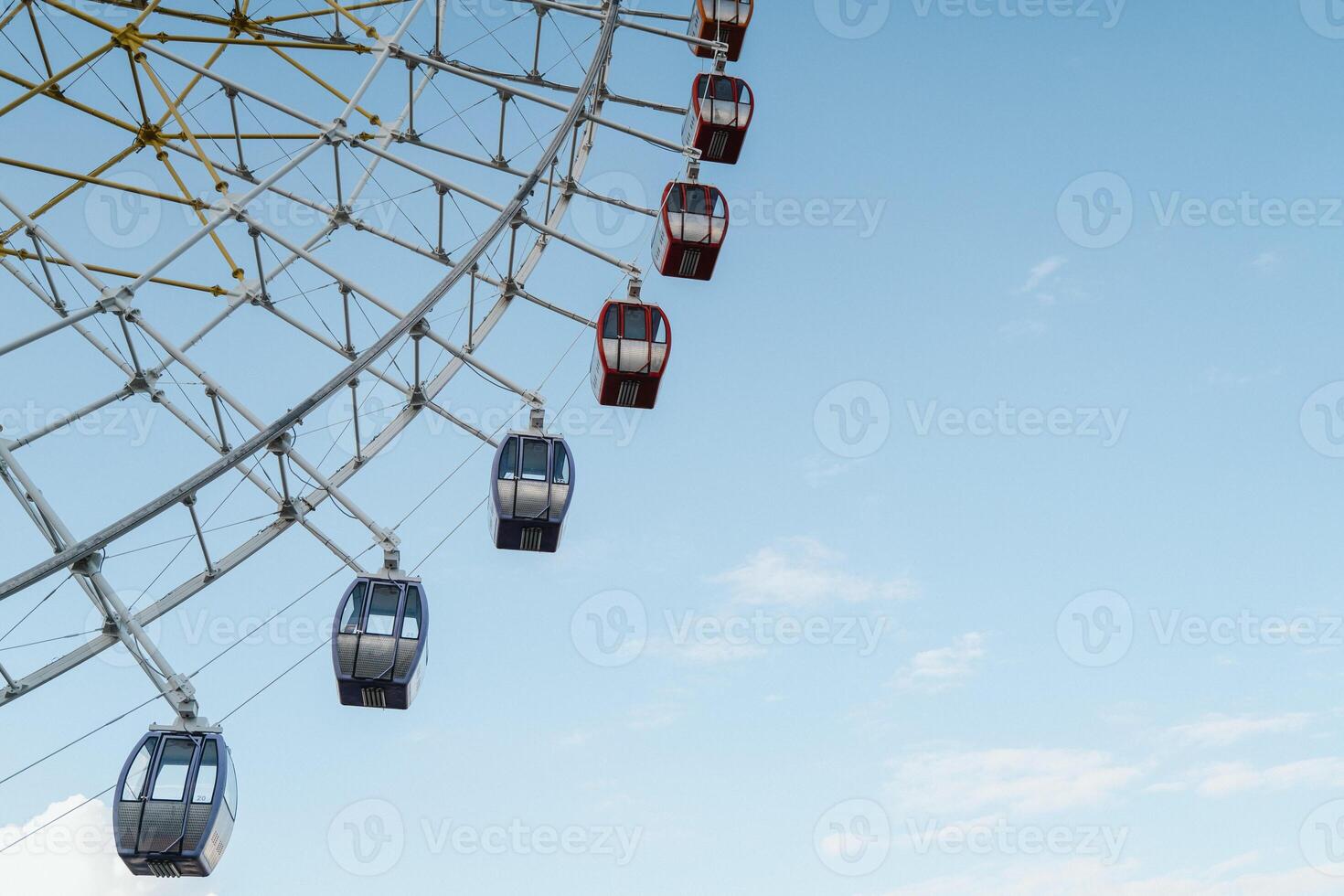 Part of the colorful Ferris wheel rises against the clear sky, inviting guests to the amusement park. photo
