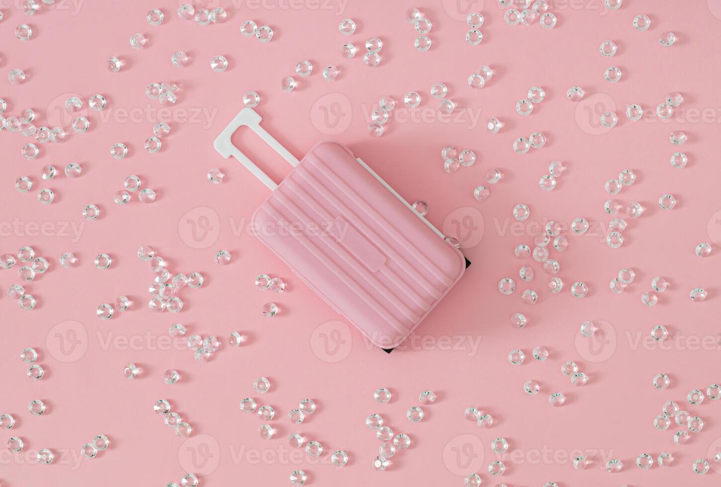 Trendy pattern composition made of diamonds with pink suitcase on pastel pink background. Minimal creative travel concept. Fancy vacation idea. Flat lay. photo