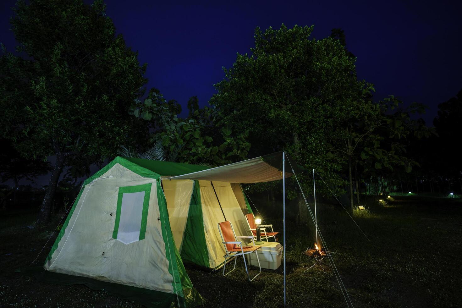 Camping tents at night, vintage cabin tents, antique oil lamps, retro chairs, and a group of camping tents with outdoor facilities photo