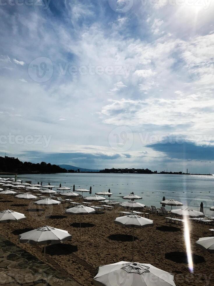 Serene beach with rows of white umbrellas and blue sky. Nesebar, Bulgaria. photo