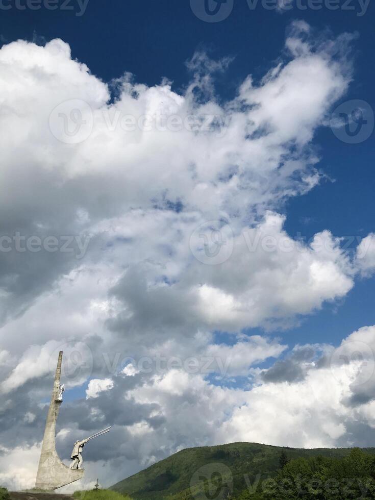 Monument hutsul with trembita in Skole under a dramatic cloudy sky in a scenic landscape. photo