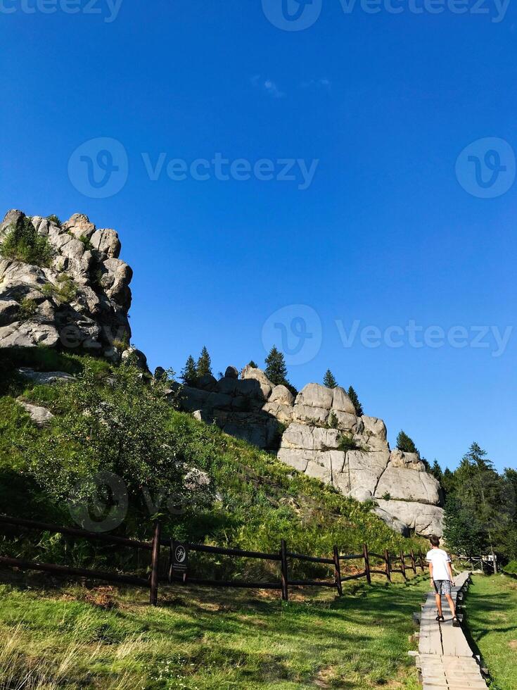 Hiker on Trail by Scenic Rock Formation in Sunny Landscape, Tustan, Ukraine. photo