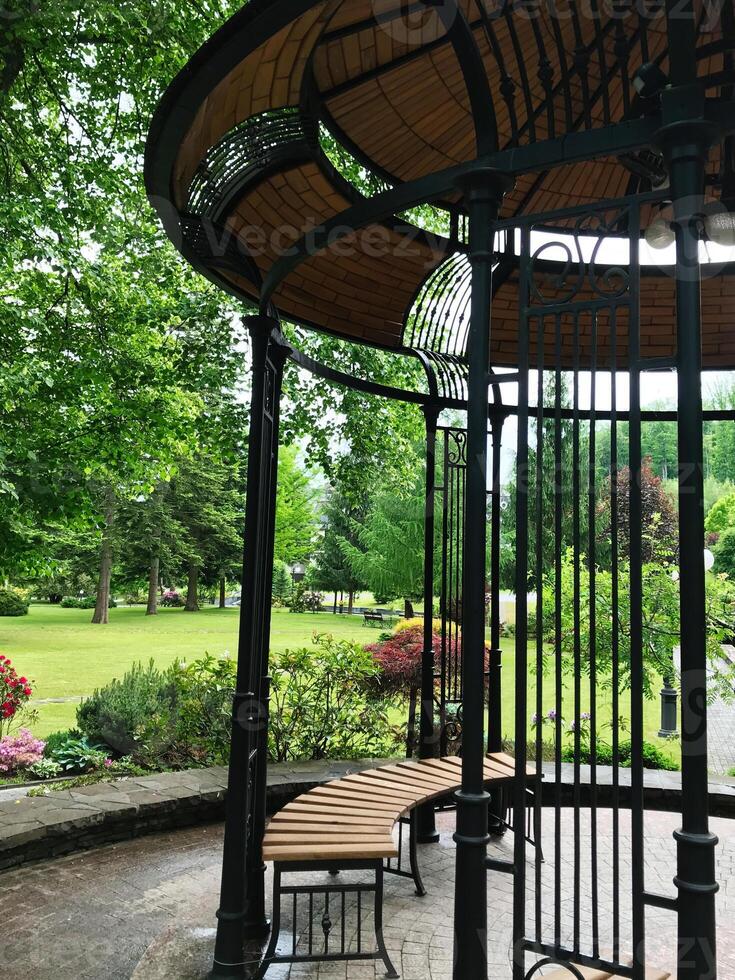 Elegant garden gazebo with wooden bench in lush park setting photo