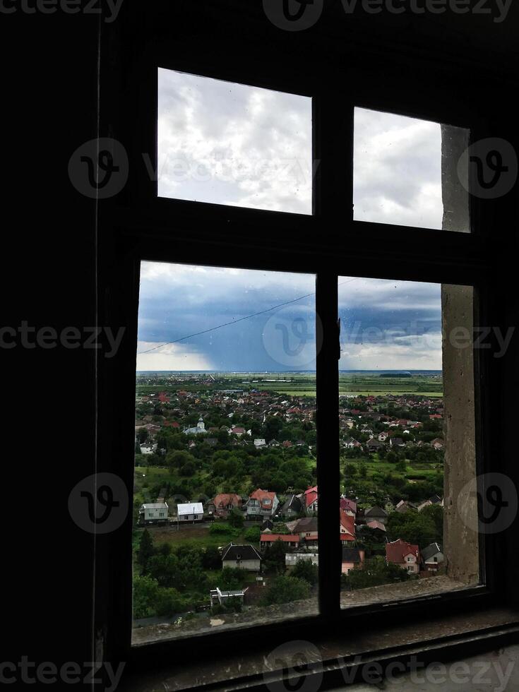 Scenic countryside view through rustic window with cloudy sky photo
