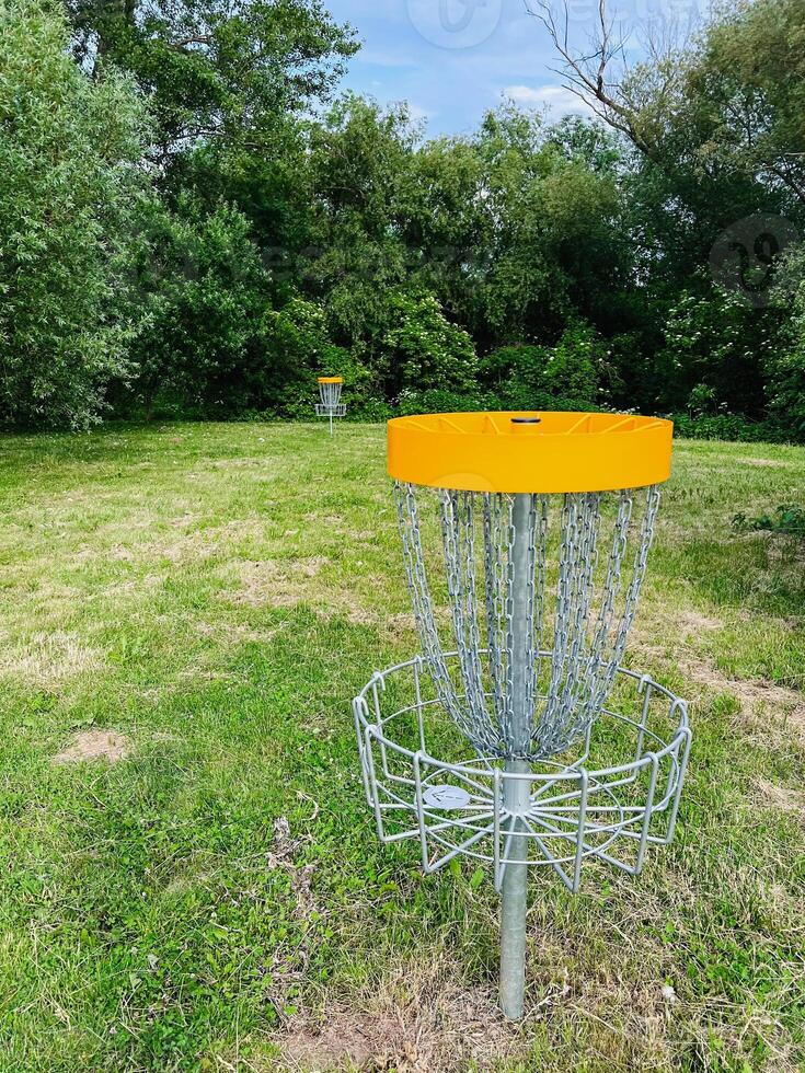 Disc golf basket in a scenic park setting with trees and grass photo
