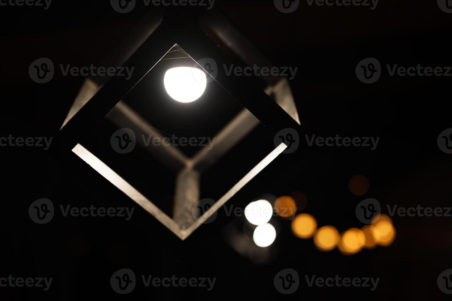 Modern geometric light fixture with glowing bulb at night photo