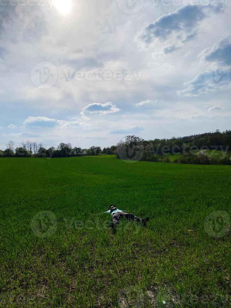 Person relaxing in a peaceful green meadow under a sunny sky photo