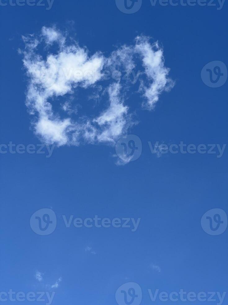 Fluffy white cloud shaped like a heart in blue sky photo