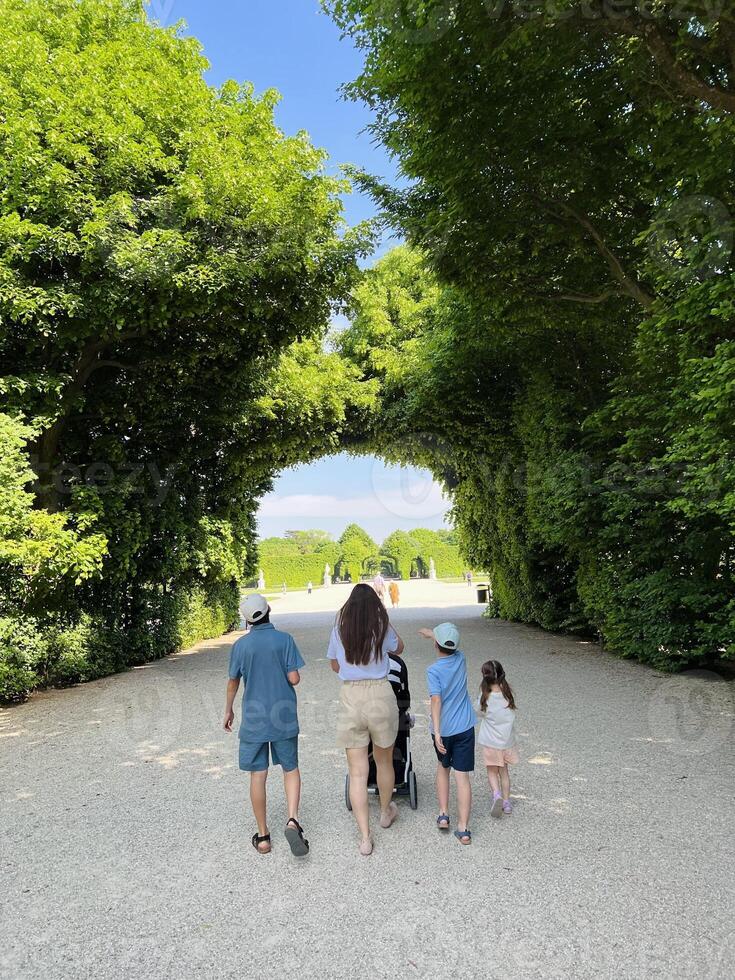 Family strolls through lush green park on sunny day in Schonbrunn palace, Austria. photo