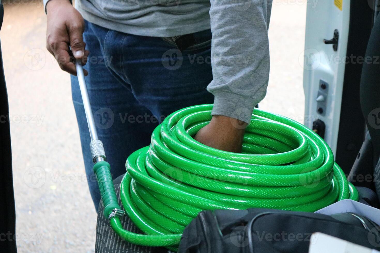 A man holding a green hose in the back of a van photo