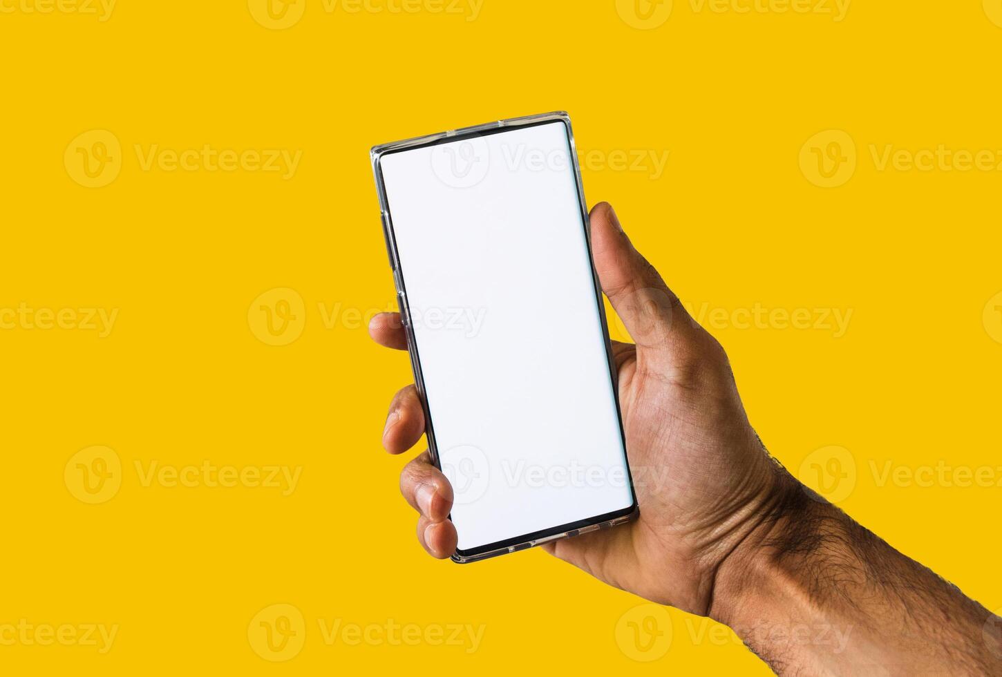 Male hands holding a mobile isolated in yellow background. Space for text or logo. photo