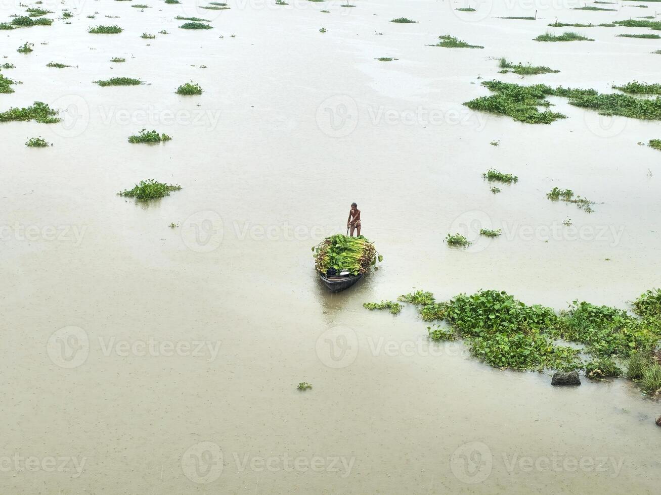 A man is standing on a boat in a flooded area photo