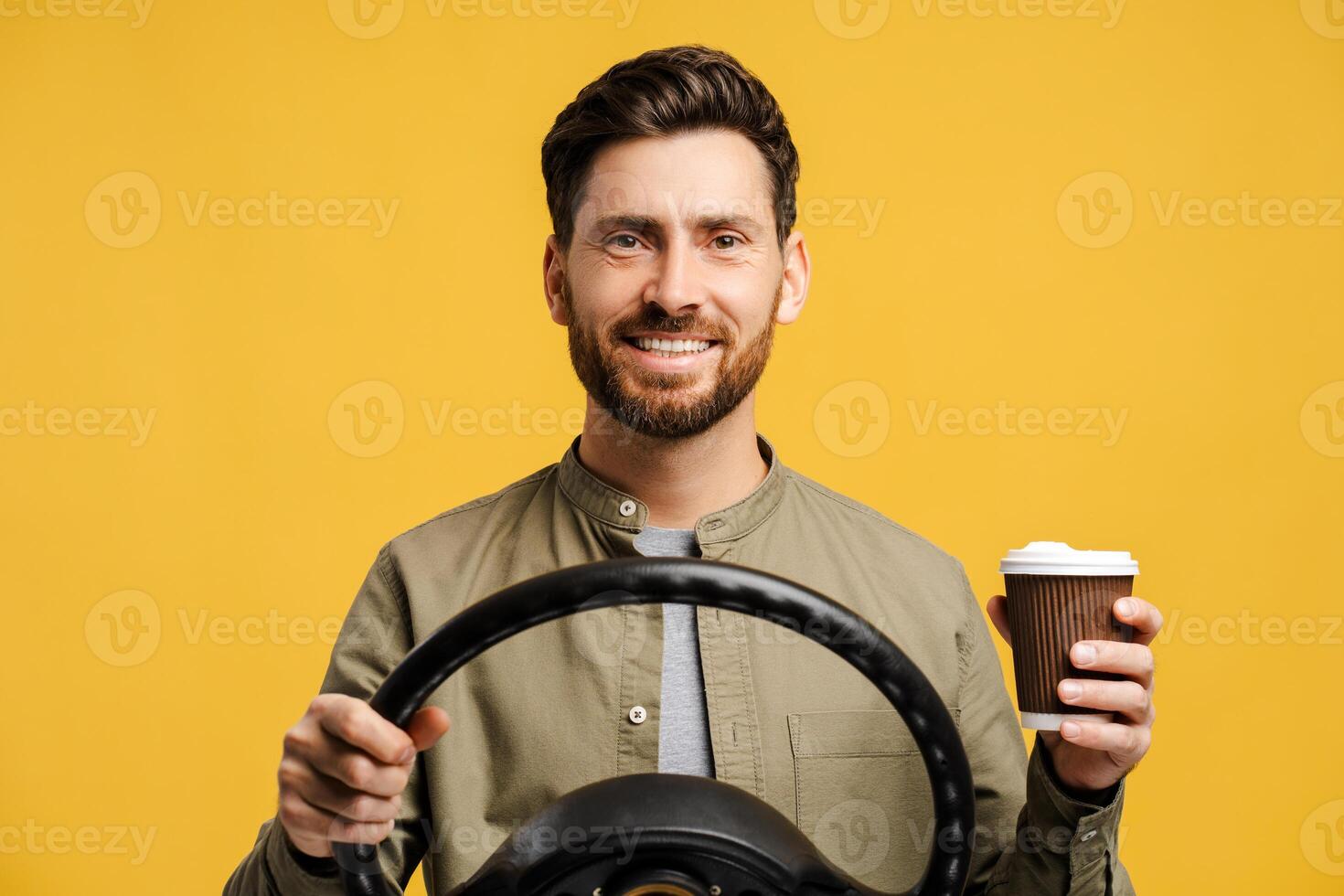 Handsome, smiling Latin man wearing eyeglasses holding steering wheel and paper cup with drink photo