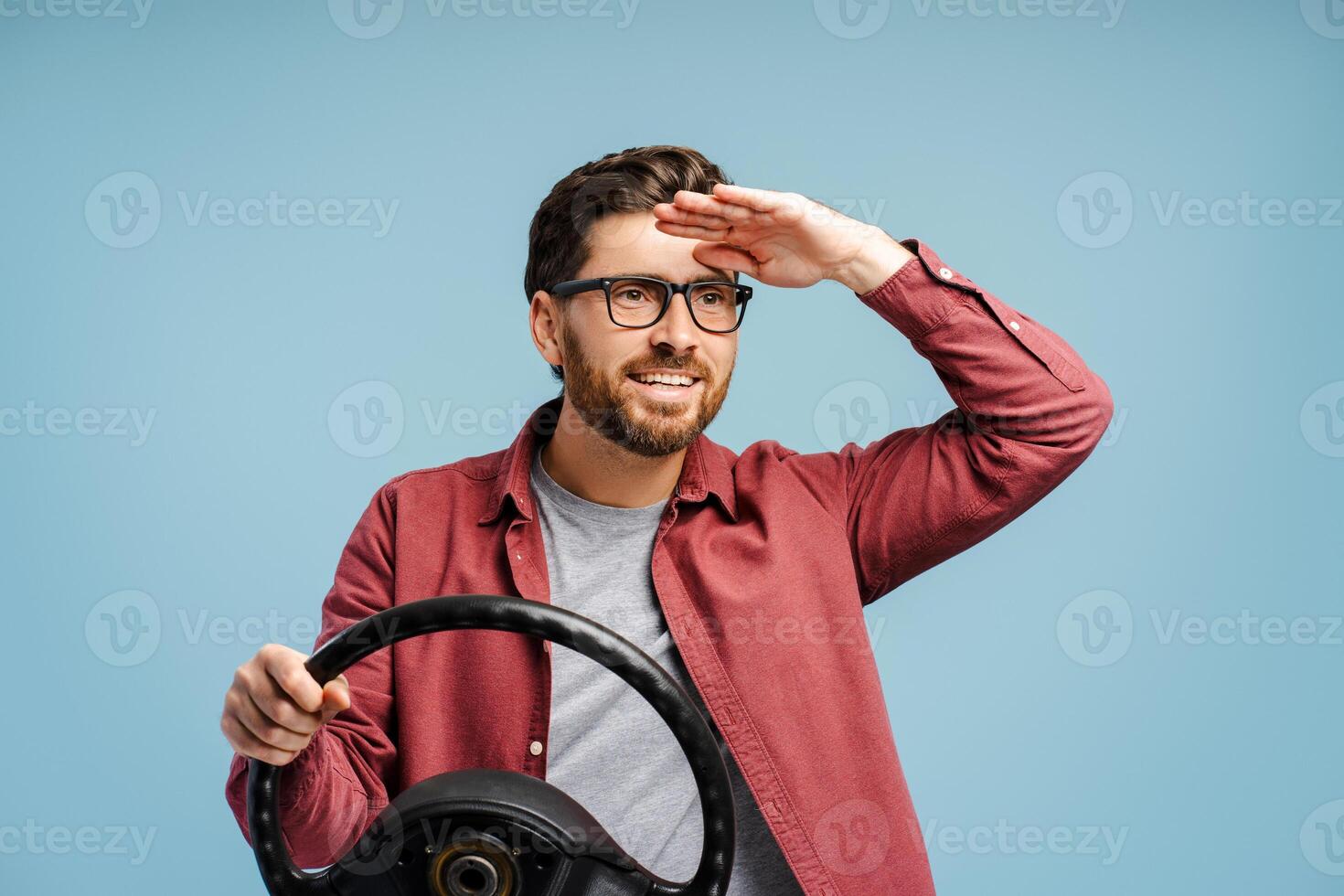 Portrait of smiling, positive Latin man, driver wearing eyeglasses, holding helm, looking away photo
