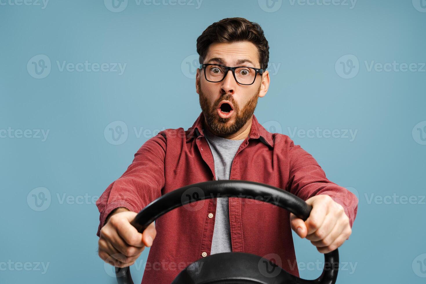 Portrait of shocked, amazed bearded man wearing eyeglasses, holding steering wheel photo