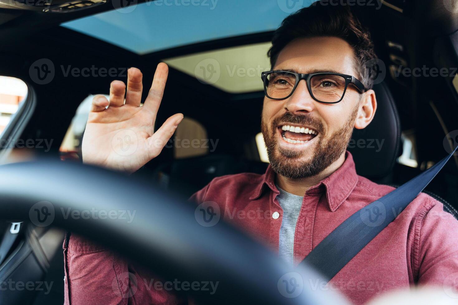 Portrait of happy, handsome businessman wearing eyeglasses driving car, looking away photo